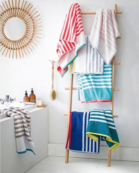 Baño con espejo sol de bambú y toallas de colores