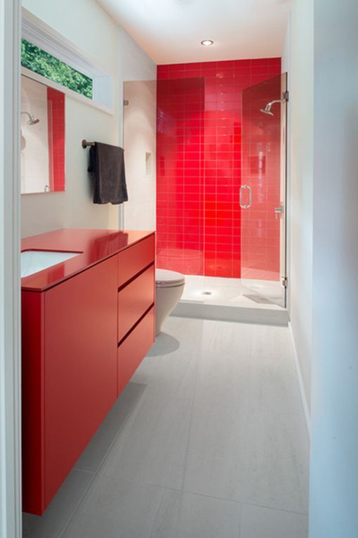 Baño moderno con predominio del color rojo y mampara de apertura abatible Fijos de ducha en baños modernos con baldosas y muebles a color
