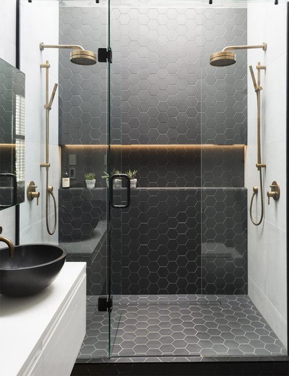Espacio de ducha con baldosas negras, mampara transparente y grifería vintage